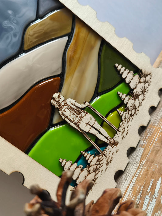 Décoration murale en bois et verre - détails de la randonneuse gravée entourée de cairns.