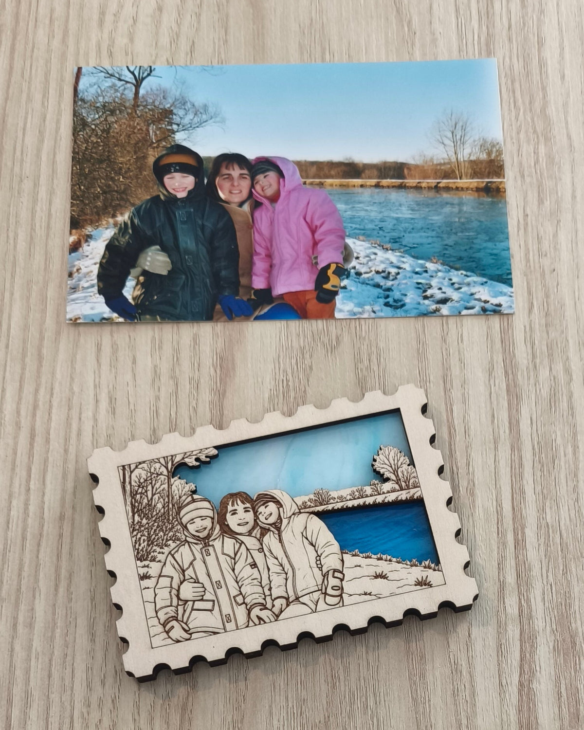 Aimant personnalisé en verre et en bois en forme de timbre représentant une famille en promenade au bord d'un canal en hiver. Au-dessus, la photo ayant servie de modèle.