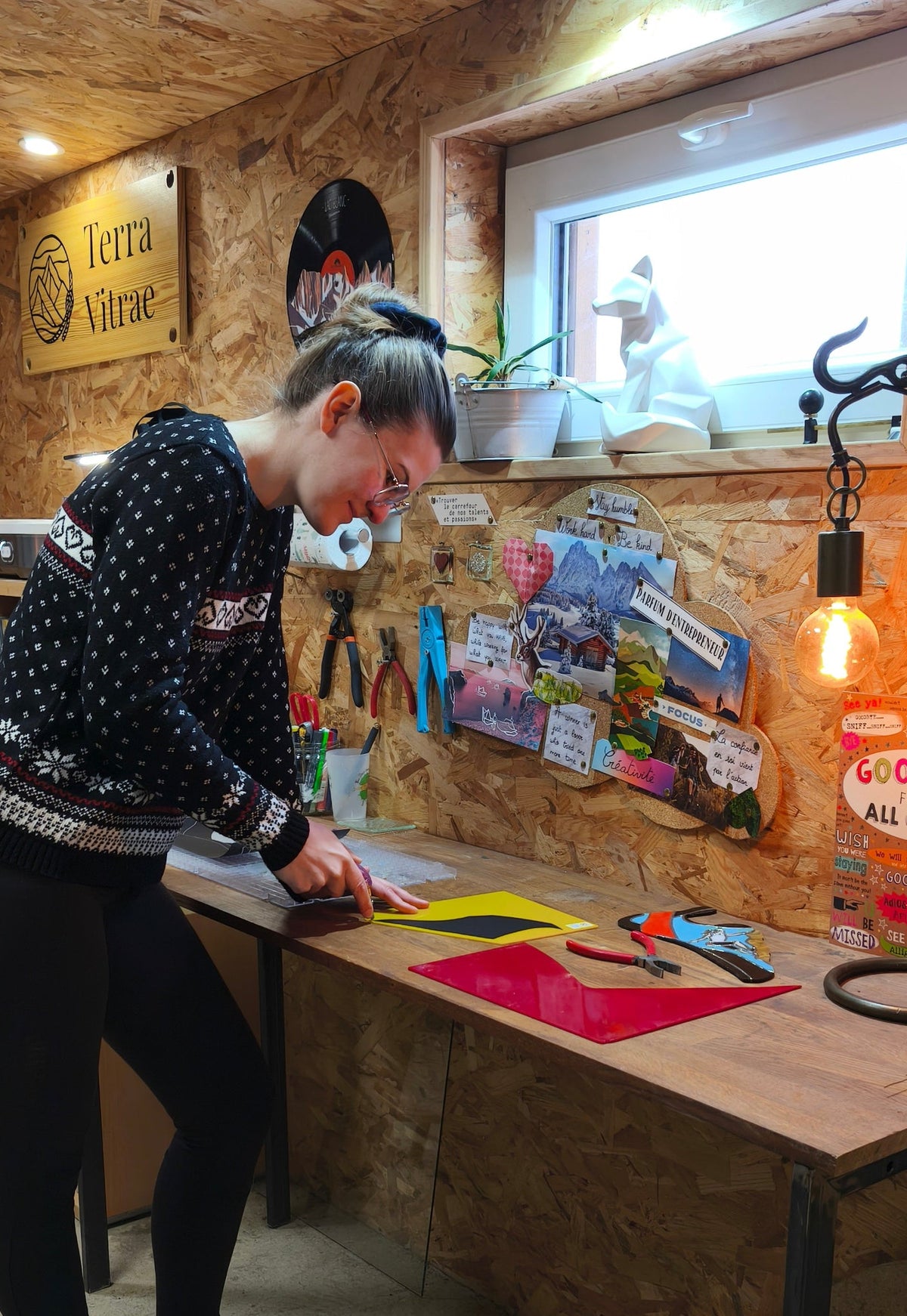 
Terra Vitrae - Décorations en vitrail et verre fondu et bois, inspirées de la nature et la montagne - L'artisane dans son atelier qui découpe du verre