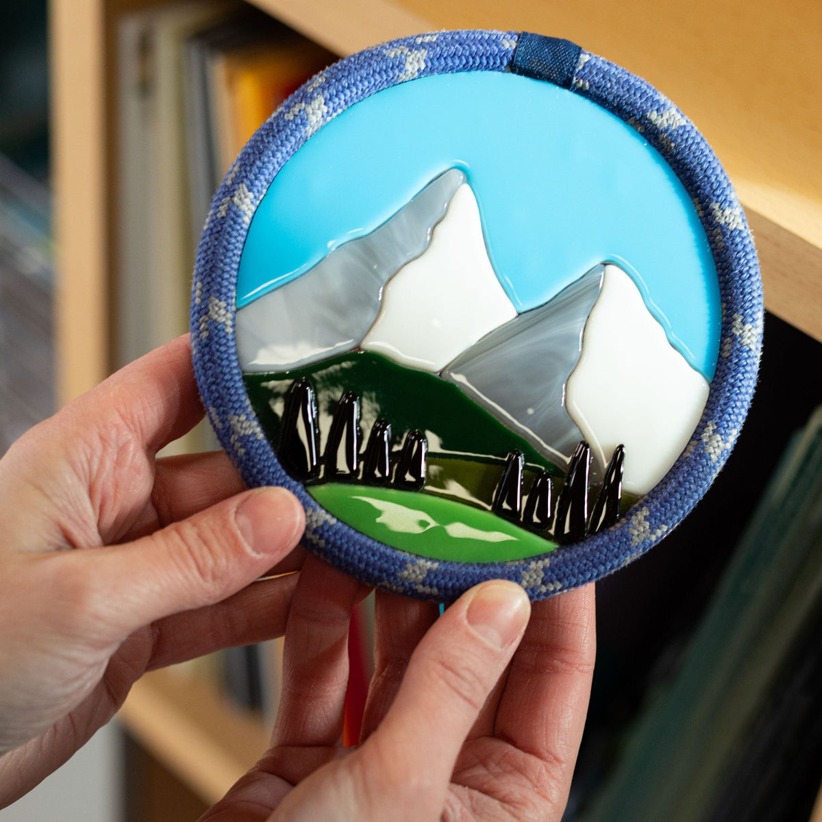 Terra Vitrae -  Une décoration représentant un paysage de montagnes en verre entouré d'une corde d'escalade