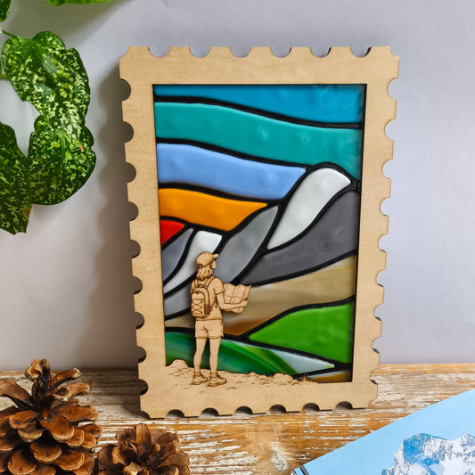 Décoration murale artisanale - paysage montagne en verre fondu - cadre en bois en forme de timbre - randonneuse et sa carte gravées. 